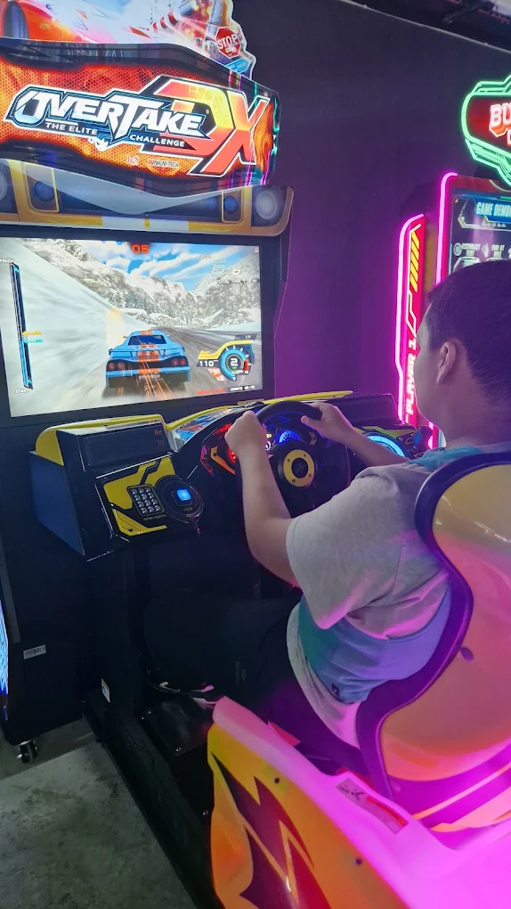 Jeune concentré sur un jeu d'arcade lors d'une sortie collective ARK